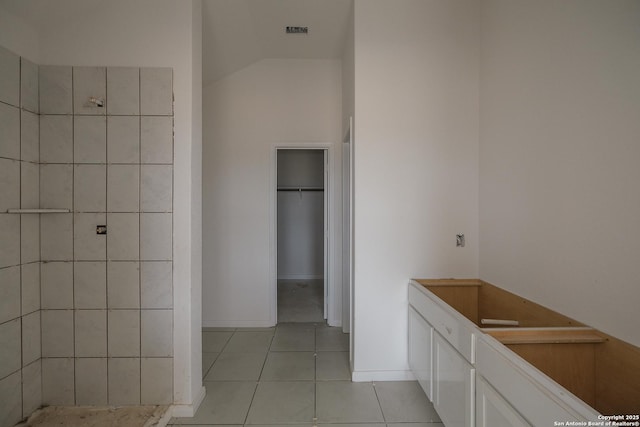 full bath with tile patterned floors, visible vents, tiled shower, a spacious closet, and vaulted ceiling