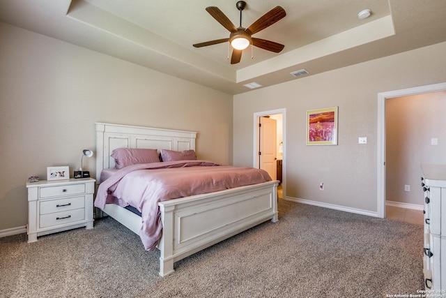 carpeted bedroom featuring a raised ceiling and ceiling fan