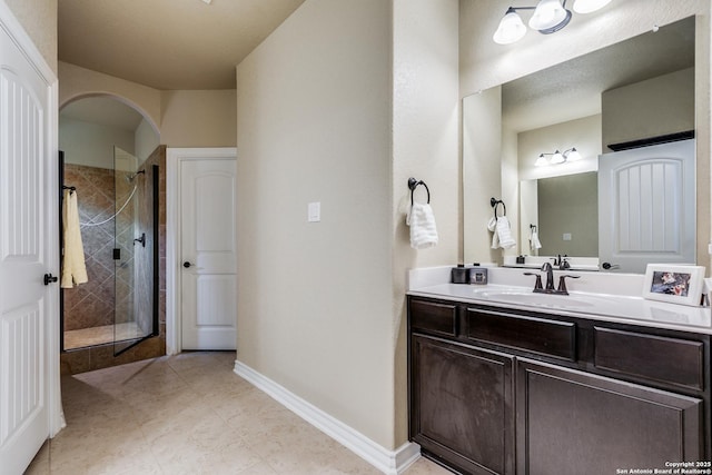 bathroom featuring a shower with door and vanity