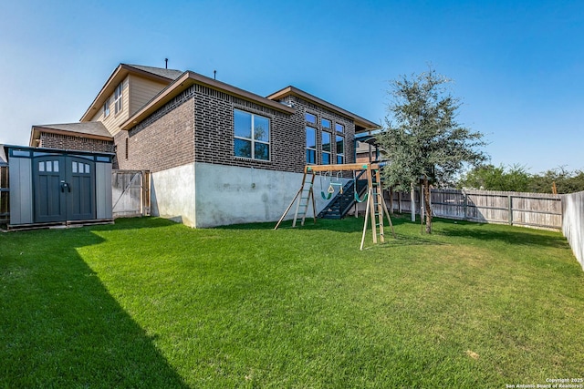 rear view of house with a yard, a playground, and a storage unit