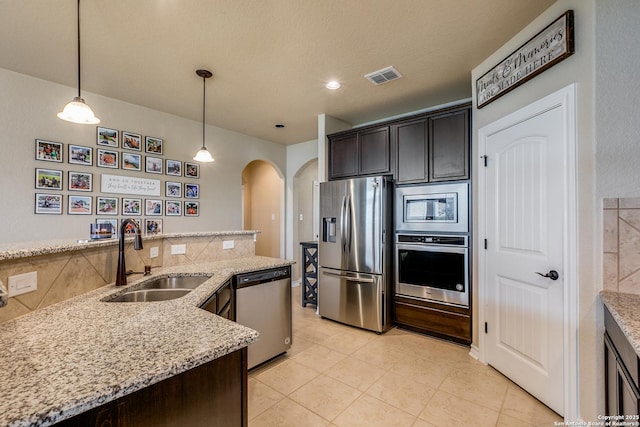 kitchen featuring dark brown cabinetry, stainless steel appliances, hanging light fixtures, and sink