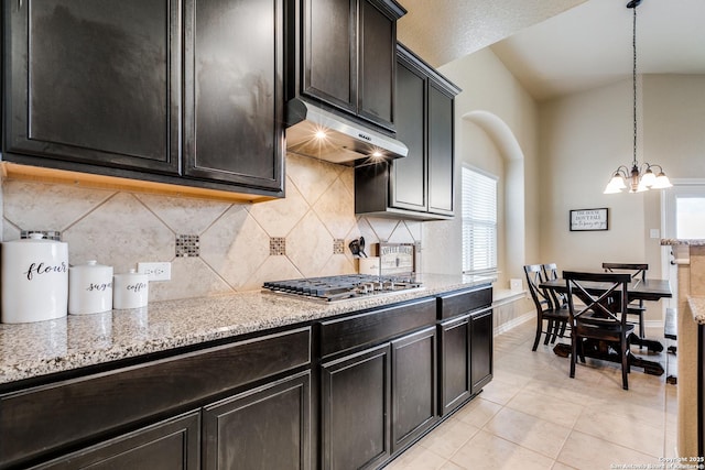 kitchen featuring hanging light fixtures, light tile patterned floors, light stone counters, stainless steel gas cooktop, and a chandelier