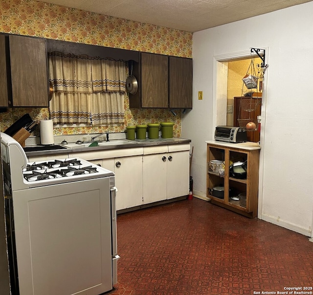 kitchen featuring sink, backsplash, gas range gas stove, and dark brown cabinets