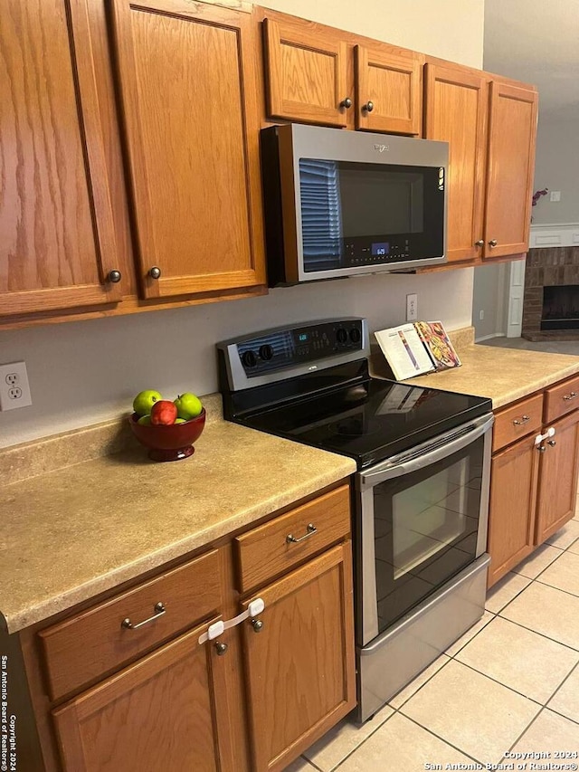 kitchen with a fireplace, appliances with stainless steel finishes, and light tile patterned flooring