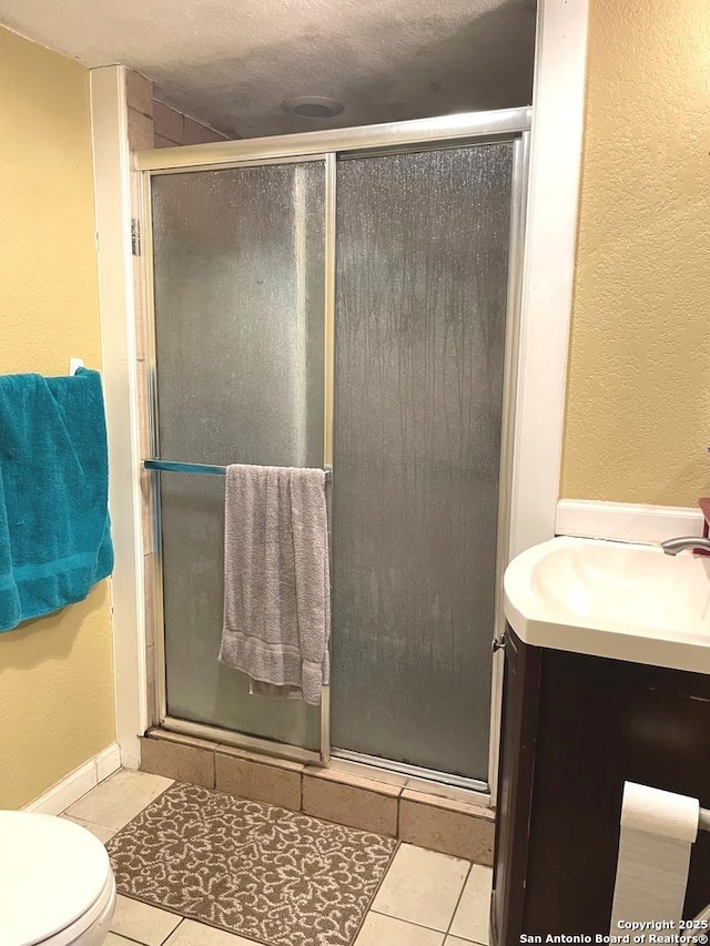 bathroom featuring toilet, tile patterned floors, walk in shower, and sink