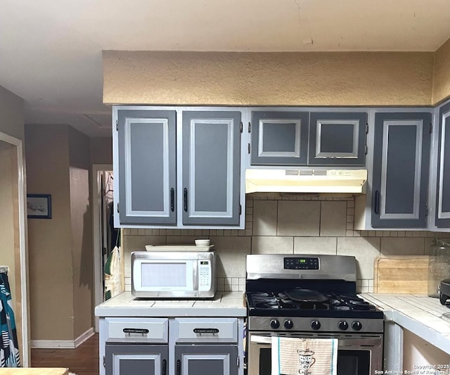 kitchen with gray cabinetry, dark hardwood / wood-style flooring, backsplash, and gas range