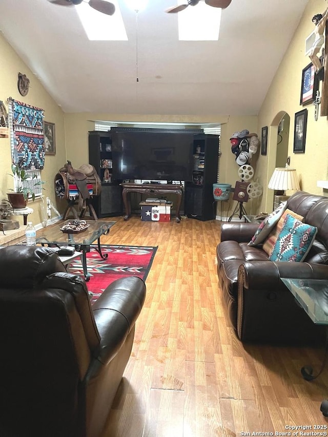 living room featuring hardwood / wood-style floors, lofted ceiling with skylight, and ceiling fan