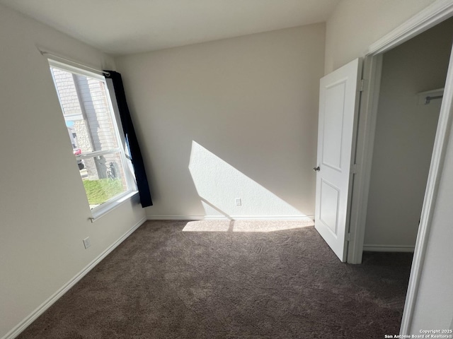 spare room featuring dark colored carpet and a healthy amount of sunlight