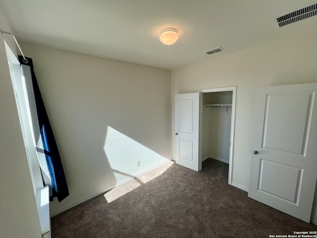 unfurnished bedroom with a closet and dark colored carpet