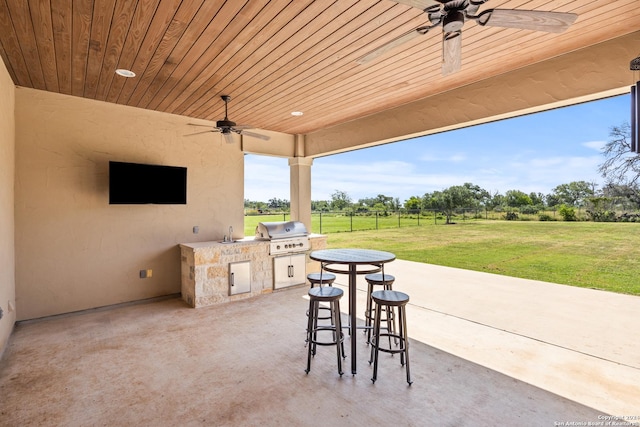 view of patio featuring ceiling fan, exterior kitchen, sink, and grilling area