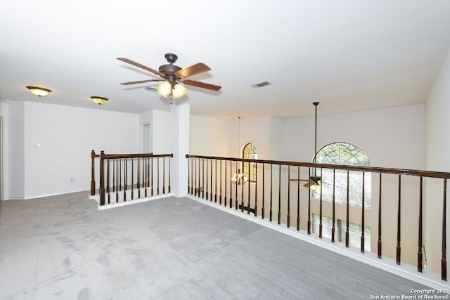 carpeted spare room with ceiling fan with notable chandelier