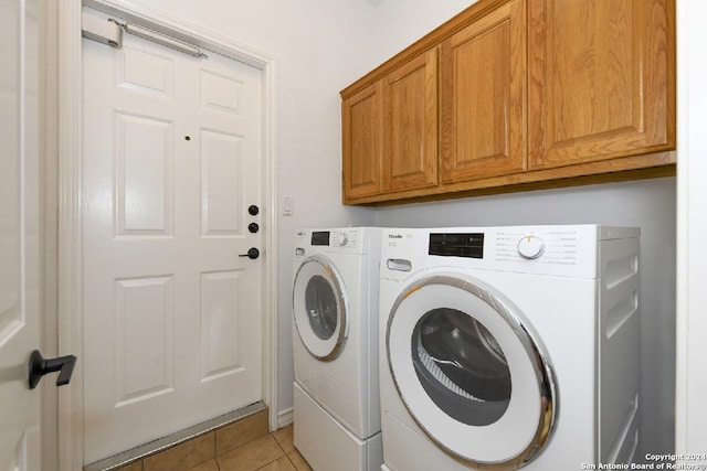 laundry area featuring cabinets, washing machine and dryer, and light tile patterned floors