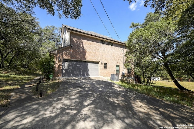 view of property exterior with a garage and central AC unit