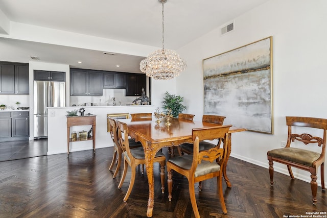 dining room with dark parquet flooring and a chandelier