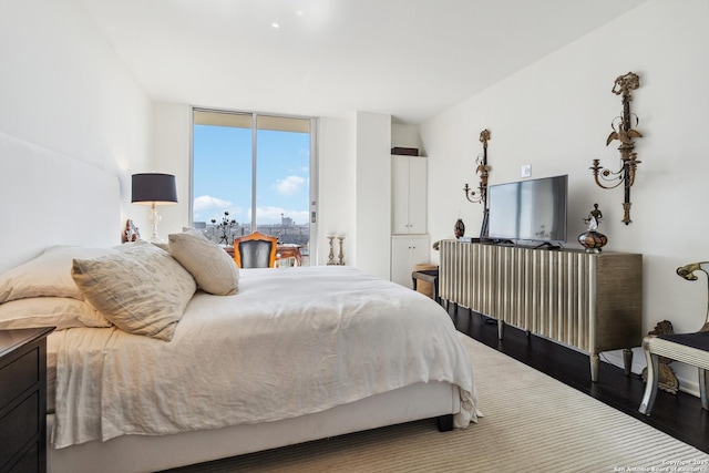 bedroom with hardwood / wood-style flooring and a wall of windows