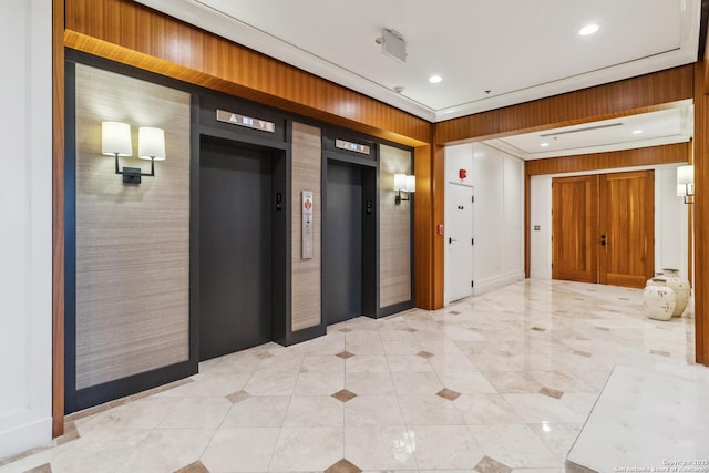 corridor with elevator and wood walls