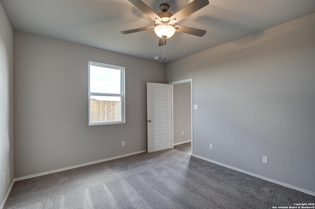 empty room with ceiling fan and dark colored carpet