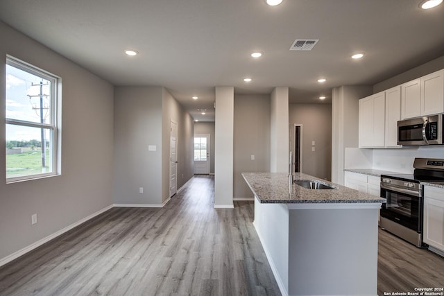 kitchen featuring a center island with sink, white cabinets, stone countertops, and appliances with stainless steel finishes