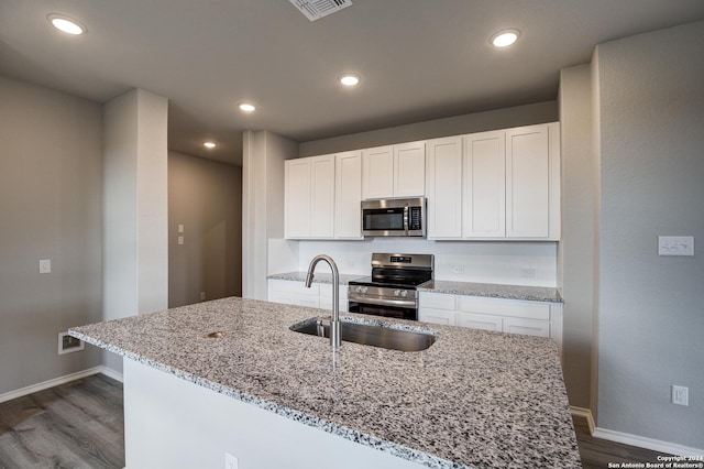 kitchen with light stone countertops, appliances with stainless steel finishes, white cabinetry, and sink