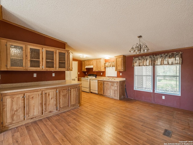 kitchen with white appliances, sink, decorative light fixtures, an inviting chandelier, and light hardwood / wood-style flooring