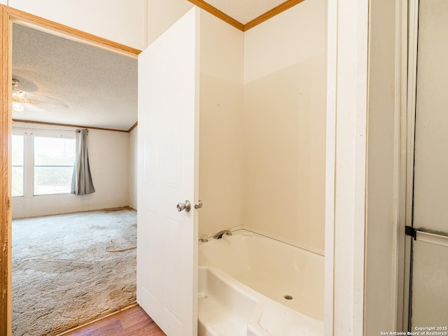 bathroom featuring hardwood / wood-style floors, a bath, a textured ceiling, and ornamental molding