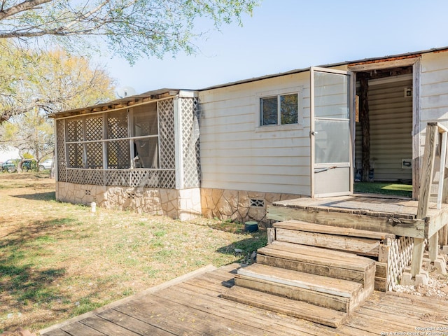 back of house featuring an outbuilding, a sunroom, and a wooden deck