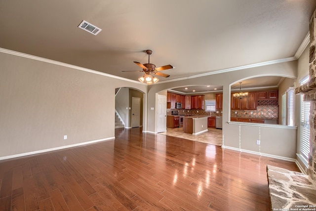 unfurnished living room featuring light hardwood / wood-style flooring, ceiling fan with notable chandelier, and ornamental molding