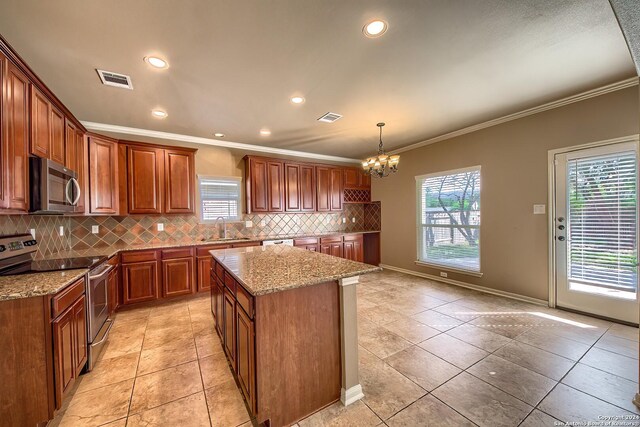 kitchen with appliances with stainless steel finishes, sink, decorative light fixtures, a notable chandelier, and a kitchen island