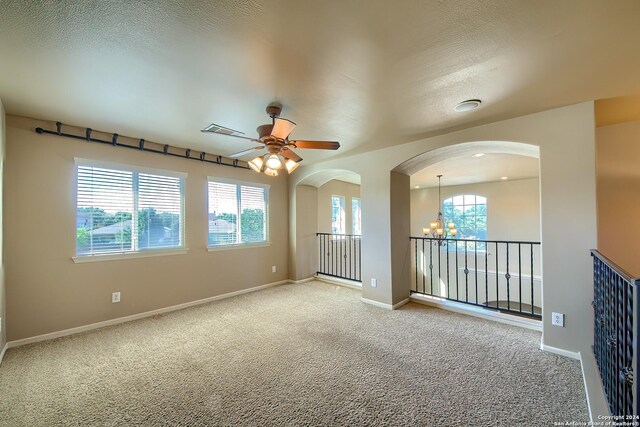 unfurnished room with a textured ceiling, ceiling fan with notable chandelier, and carpet floors