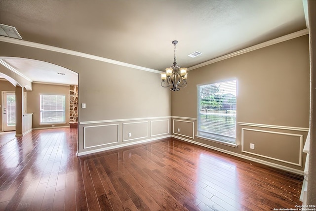 spare room with a chandelier, dark hardwood / wood-style flooring, a wealth of natural light, and ornamental molding