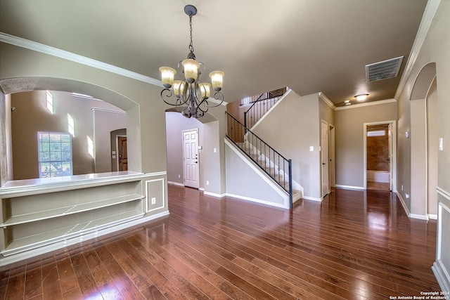 spare room featuring ornamental molding, dark wood-type flooring, and an inviting chandelier