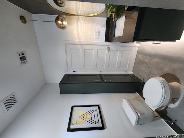 bathroom with tile walls and toilet