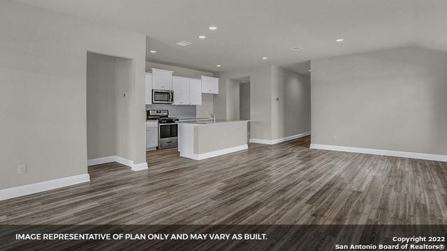 kitchen featuring white cabinets, a center island with sink, appliances with stainless steel finishes, tasteful backsplash, and dark hardwood / wood-style flooring