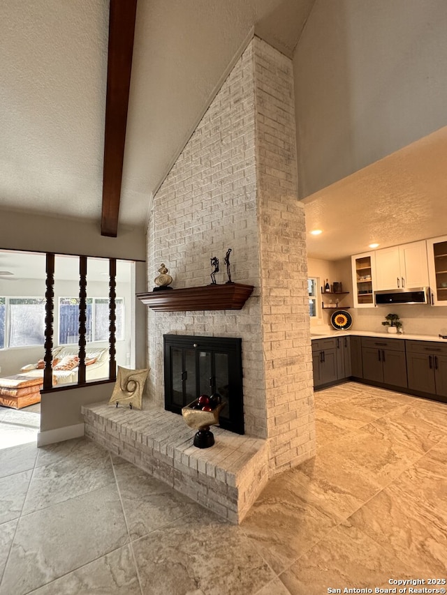 living room featuring beamed ceiling, high vaulted ceiling, and a brick fireplace