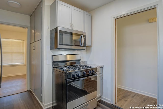 kitchen with stainless steel appliances, white cabinetry, and light hardwood / wood-style floors