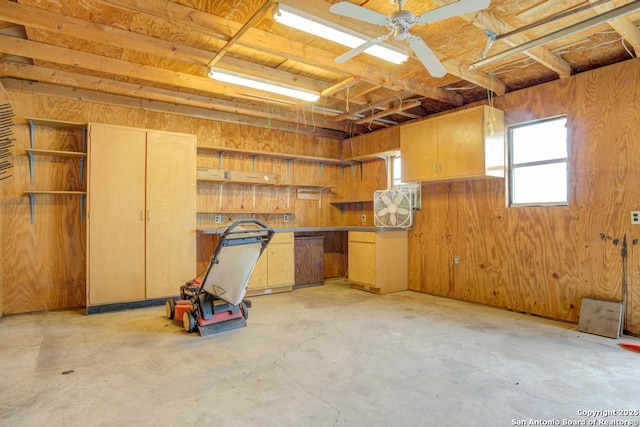 garage with ceiling fan and wood walls