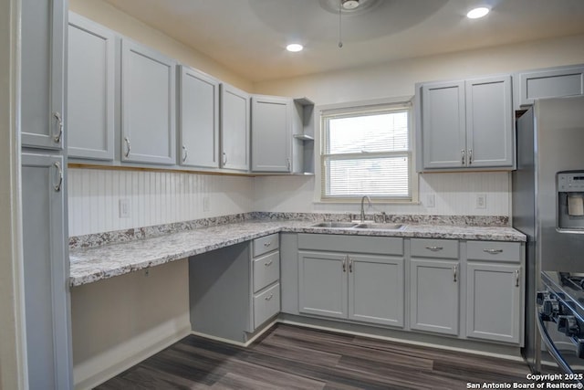 kitchen with appliances with stainless steel finishes, gray cabinetry, dark wood-type flooring, and sink