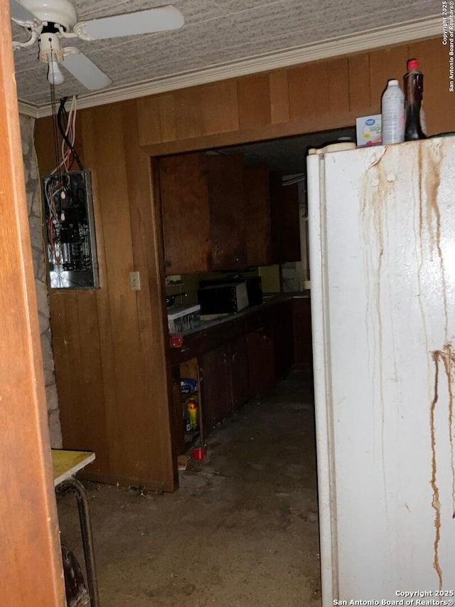 kitchen featuring white fridge, concrete flooring, ornamental molding, and wooden walls