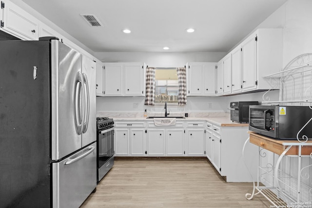 kitchen featuring white cabinets, stainless steel appliances, light hardwood / wood-style floors, and sink