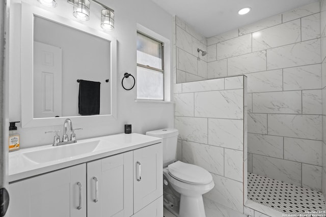 bathroom featuring tiled shower, vanity, and toilet