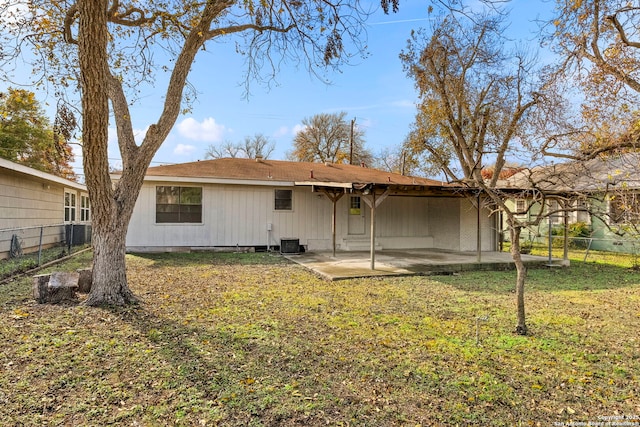 rear view of property with cooling unit, a yard, and a patio