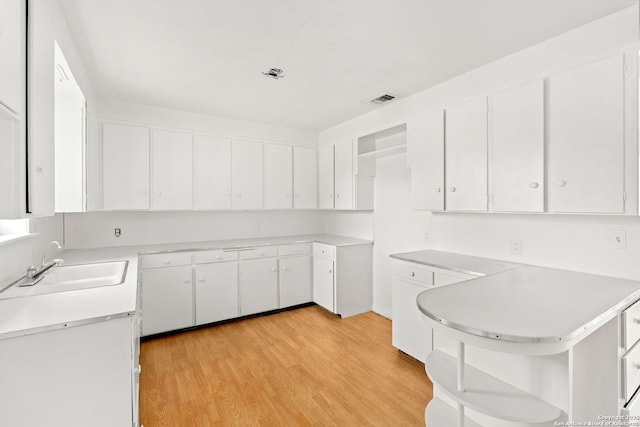 kitchen featuring light hardwood / wood-style flooring, white cabinets, and sink