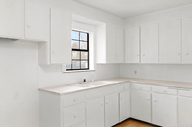 kitchen featuring light hardwood / wood-style flooring, white cabinetry, and sink