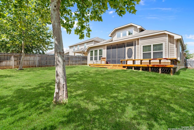 rear view of house featuring a wooden deck, a sunroom, and a yard