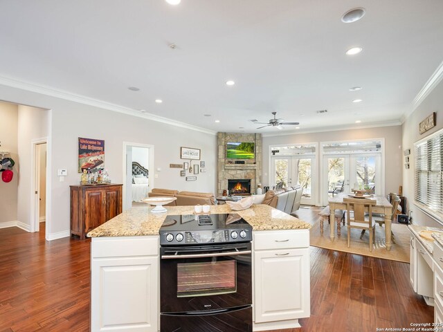 kitchen with ornamental molding, black range with electric cooktop, ceiling fan, white cabinets, and a center island