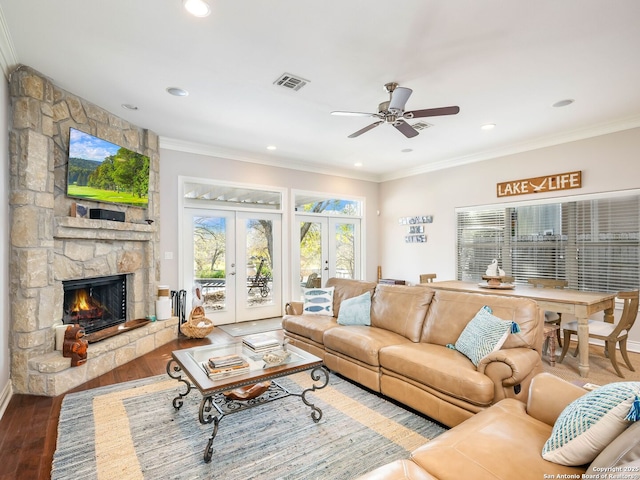 living room with french doors, crown molding, ceiling fan, a fireplace, and wood-type flooring