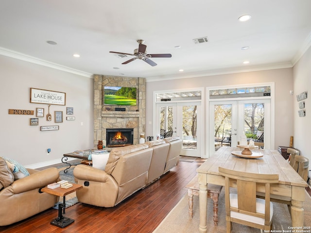 living room featuring ceiling fan, french doors, dark hardwood / wood-style flooring, a fireplace, and ornamental molding