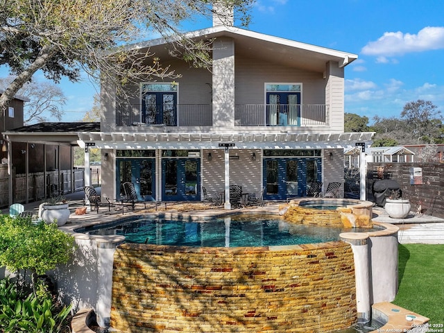 rear view of house with a pergola, a balcony, a patio, and a pool with hot tub