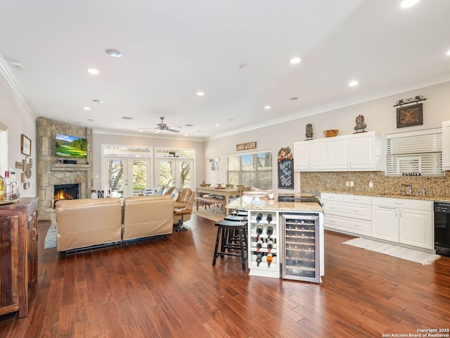 kitchen featuring tasteful backsplash, light stone counters, a kitchen island, white cabinets, and wine cooler