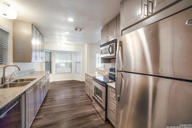 kitchen with dark hardwood / wood-style flooring, sink, stainless steel appliances, and a textured ceiling